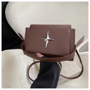 Dettaglio di una borsa a tracolla in pelle marrone con fibbia metallica a forma di stella
