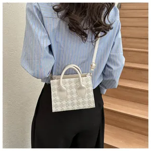 Detailed back view of a plaid tweed crossbody bag on a model with wood background