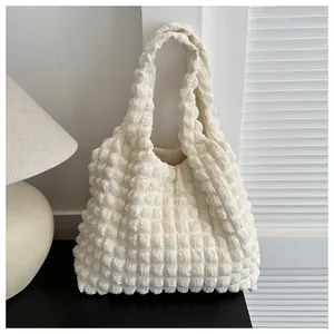 Detail view of the cream popcorn bubble texture fabric and soft shoulder strap of the tote bag