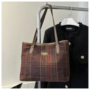 Close-up of classic checkered tote bag featuring leather handles and brand metal logo