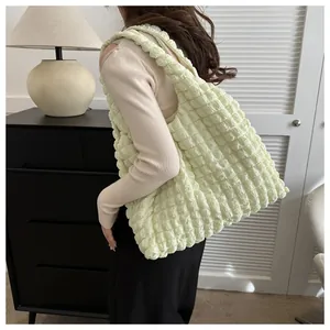 Detail of light yellow tote bag featuring a 3D bubble pleated texture and wide strap