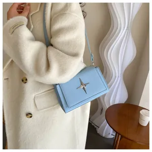 Piccola borsa a tracolla in pelle azzurra con stella su cappotto di lana bianco