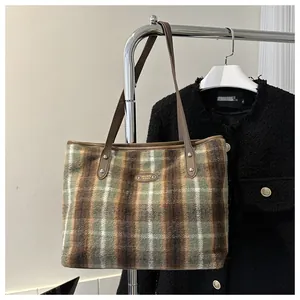 Macro view of textured plaid tote bag fabric with leather straps and metal rivets