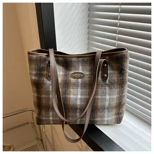 Detail of vintage plaid tote bag with metal brand plaque and brown leatherette trim