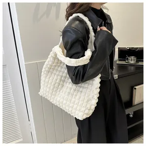 Detail of white popcorn textured tote bag with wide strap on model in black jacket