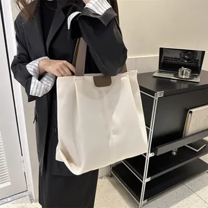 Bolso tote minimalista de lona crema con asas marrones y gran capacidad de espacio