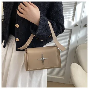 Dettaglio borsa beige con emblema a stella argento e tracolla larga in pelle liscia