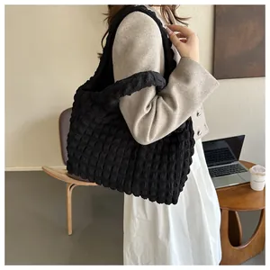 Side view of a large black popcorn texture shoulder bag worn in a chic office setting
