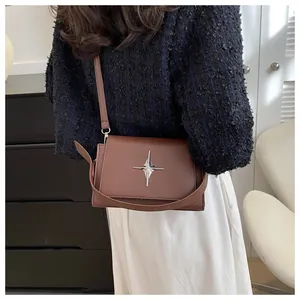 Dettaglio di una borsa a tracolla marrone vintage con fibbia in metallo a forma di stella