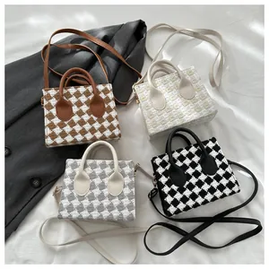 Flat lay of mini plaid crossbody handbags in four colors on a white fabric background