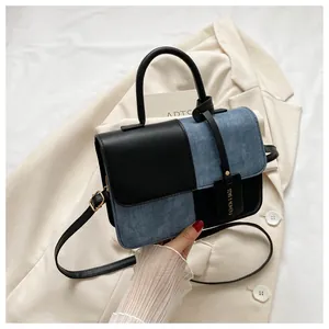 Dettaglio della borsa patchwork in pelle nera e denim blu con finiture in metallo dorato