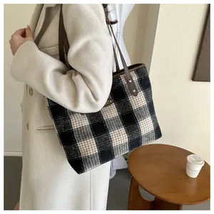 Detail of plaid tote bag featuring textured wool fabric and brown leather straps