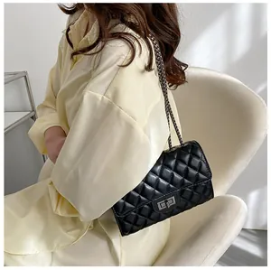 Close-up of black quilted shoulder bag featuring a metallic turn-lock and chain strap