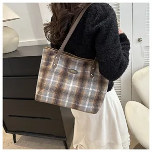 Close-up of vintage plaid tote bag featuring leather straps and metal logo detailing