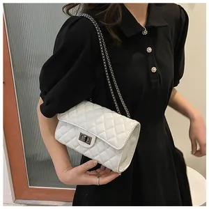 Detail of white quilted crossbody bag with silver twist lock and chain strap on model