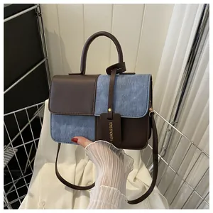 Dettaglio borsa squadrata in pelle marrone e denim con manico e tracolla rimovibile