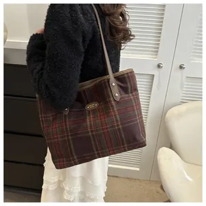 Detailed side view of checkered tote bag with leather trim on model in home setting