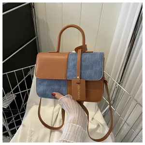 Dettaglio del design patchwork in pelle marrone e denim blu sulla borsa quadrata di moda