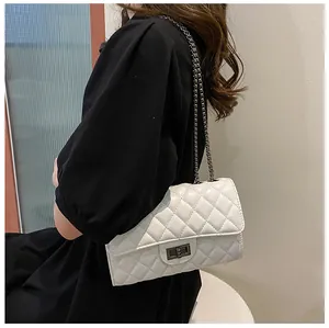 Detail view of the white quilted chain bag with a vintage metal turn-lock on a model