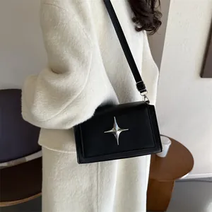 Borsa a tracolla nera minimalista con decorazione a stella su cappotto bianco