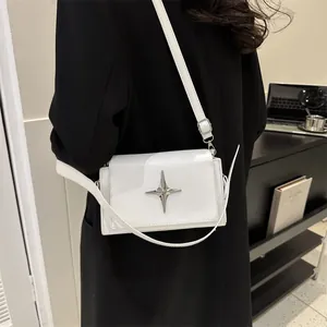 Piccola borsa quadrata bianca minimalista con stella d'argento indossata da una modella