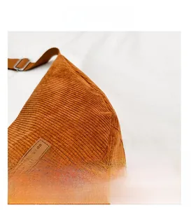 Detailed macro view of brown corduroy fabric and leather fashion logo patch on the bag