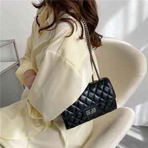 Elegant black quilted crossbody bag with diamond pattern and metal chain strap on model