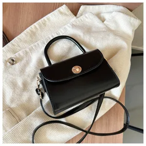 Detailed macro view of black leather mini square bag with golden metallic twist lock buckle