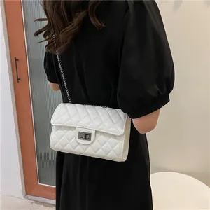 White quilted crossbody bag with silver chain strap shown on model in minimal interior