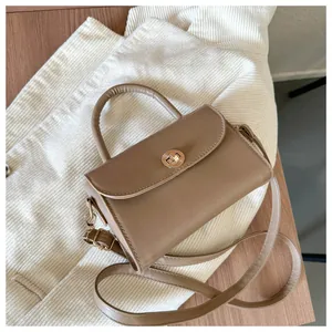 Detail view of khaki retro small square bag with golden round twist lock and handle