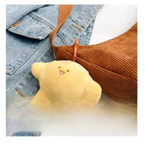 Detail presentation of plush yellow star charm with orange hook on corduroy bag