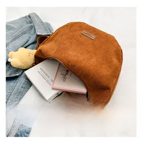 Interior capacity detail of brown corduroy crossbody bag holding books and tablet