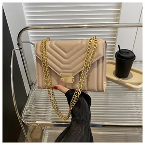 Detail view of V-shaped quilted beige shoulder bag with gold chain strap and lock