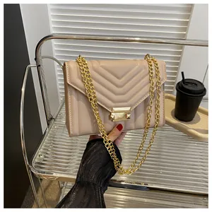 Detail of beige quilted shoulder bag with gold chain strap and square metal clasp