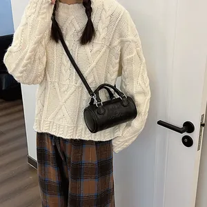 Minimalist black leather Boston bag with embossed lettering and adjustable strap