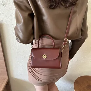 Vintage reddish brown small square bag with golden lock shown on model's shoulder