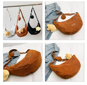 Detailed view of corduroy crescent crossbody bags in brown, white and black colors