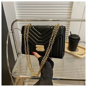 Detail of black quilted shoulder bag with V-shaped stitching and golden chain strap