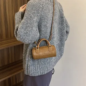 Brown leather boston handbag with embossed letters and adjustable shoulder strap