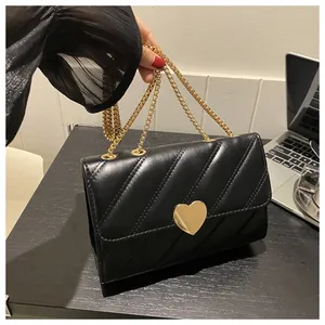 Detail of black quilted leather shoulder bag featuring a large gold heart-shaped metal buckle
