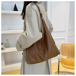Close-up of a large brown leather hobo bag with vertical stitching and thin strap