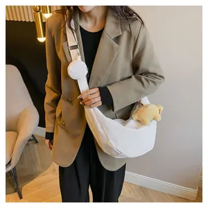 Detail of white corduroy dumpling bag with round pouch and cute bear pendant accessory