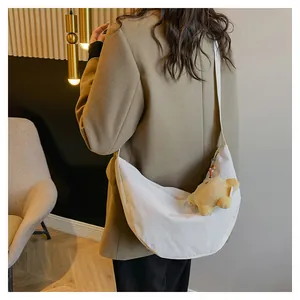 Detailed side view of white corduroy crescent bag with a cute yellow bear pendant