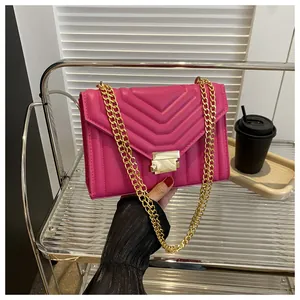 Detail of rose pink quilted crossbody bag featuring V-shaped texture and gold chain