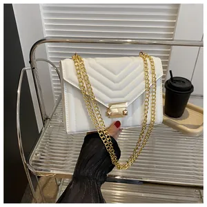 Detail of white quilted crossbody bag featuring V-shaped stitching and golden chain strap