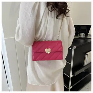 Rose red quilted crossbody bag with heart-shaped gold buckle worn by a model