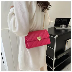 Detail of rose red crossbody bag with golden heart clasp and stylish quilted pattern