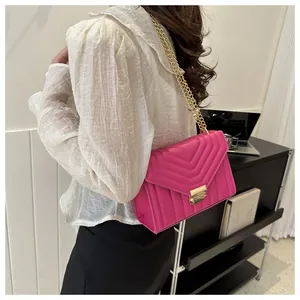 Detail view of pink quilted leather crossbody bag with gold chain strap on a model