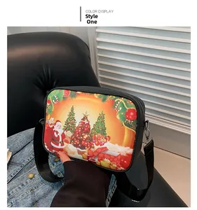 Detalle del bolso bandolera cuadrado con estampados festivos de Papá Noel y árboles