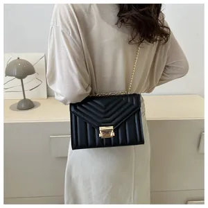 Close-up of black quilted chain shoulder bag with elegant gold hardware on a model